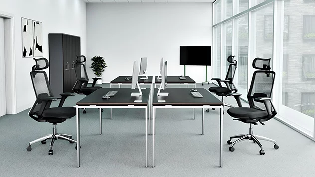 Krzesła obrotowe zostały umieszczone przy biurkach, w otoczeniu szaf, tworząc stanowisko pracy w biurze. Za oknem - jesień.